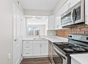 Thumbnail 2 of 32 - A kitchen with white cabinets and a brick backsplash.