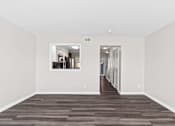 Thumbnail 14 of 32 - A long, empty hallway with a kitchen visible through the doorway.