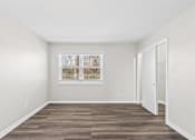 Thumbnail 18 of 32 - A room with a wooden floor and a window with blinds.