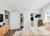 Thumbnail 19 of 32 - A bedroom with a large bed, a dresser, and a mirror.
