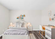 Thumbnail 27 of 32 - A bedroom with a bed, desk, and chair.