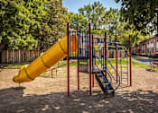 Thumbnail 31 of 32 - A playground with a yellow slide and a blue and red swing set.