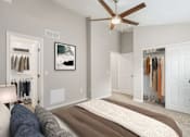 Thumbnail 11 of 32 - A bedroom with a bed, a ceiling fan, and a closet with clothes.