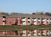Thumbnail 20 of 21 - A building with a red brick exterior is reflected in the water in front of it.