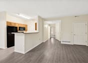 Thumbnail 20 of 54 - A spacious living room with a kitchen area and hardwood floors.