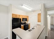 Thumbnail 27 of 54 - A kitchen with black appliances and wooden cabinets.