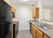 Thumbnail 26 of 54 - A kitchen with a black refrigerator and wooden cabinets.