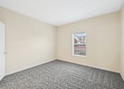 Thumbnail 38 of 54 - A room with a carpeted floor and a window showing a building outside.