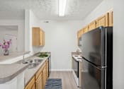 Thumbnail 2 of 54 - A kitchen with a black refrigerator and wooden cabinets.
