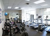 Thumbnail 10 of 25 - A gym with a variety of exercise equipment including treadmills, stationary bikes, and weight machines.