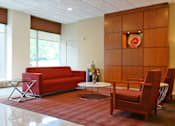 Thumbnail 14 of 25 - A red couch sits in a room with a wooden panel wall and a painting on it.