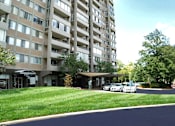 Thumbnail 20 of 25 - A tall residential building with a parking lot in front.