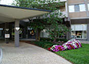 Thumbnail 21 of 25 - A tall building with a lot of windows and a small garden in front.