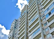 Thumbnail 18 of 25 - A tall residential building with balconies and windows.