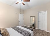 Thumbnail 9 of 44 - A bedroom with a bed, a ceiling fan, and a mirror.