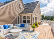 Thumbnail 27 of 46 - A house with a wooden deck and a white couch with blue pillows.