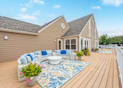 Thumbnail 28 of 46 - A house with a deck and a white sofa with blue cushions.