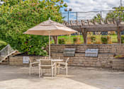 Thumbnail 31 of 46 - A patio with a table, chairs and an umbrella.