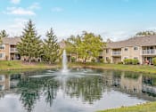 Thumbnail 35 of 46 - A fountain in the middle of a pond in front of apartment buildings.
