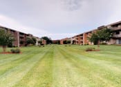 Thumbnail 17 of 18 - Lawn area with exterior view of apartment complex at Gainsborough Court Apartments, Fairfax
