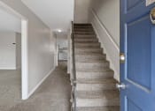Thumbnail 52 of 69 - a staircase with a blue door in a house with carpeted stairs