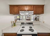 Thumbnail 6 of 37 - A kitchen with a stove top oven and wooden cabinets.