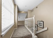 Thumbnail 30 of 53 - A hallway with a staircase and pictures on the wall.