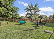 Thumbnail 6 of 53 - A park with a bench, trees, and a fence.