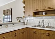 Thumbnail 26 of 53 - A kitchen with wooden cabinets and a white countertop.
