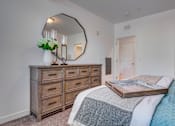 Thumbnail 11 of 38 - A bedroom with a bed, dresser, and mirror.