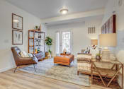 Thumbnail 4 of 38 - A living room with a chair, a table, and a rug.
