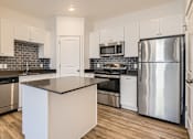 Thumbnail 12 of 38 - A kitchen with a black countertop and stainless steel appliances.