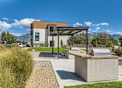 Thumbnail 2 of 20 - a picnic area with a grill and a building with mountains in the background