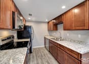Thumbnail 13 of 18 - A kitchen with wooden cabinets and granite countertops.