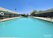 Thumbnail 6 of 18 - A pool with a blue tinted water and a white inflatable ring floating in it.