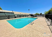 Thumbnail 7 of 18 - A pool with a blue tinted water and a black fence around it.