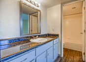 Thumbnail 7 of 13 - A bathroom with a sink, mirror, and cabinets.