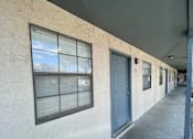 Thumbnail 5 of 27 - A long hallway with a blue door and windows.