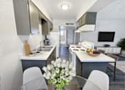 Thumbnail 9 of 27 - A modern kitchen with white cabinets and a central island.