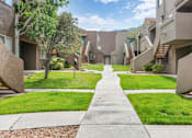 Thumbnail 23 of 28 - A concrete pathway leads through a grassy area between two rows of concrete buildings.
