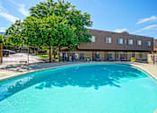 Thumbnail 14 of 28 - A large swimming pool in front of a building with a fence around it.