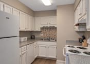 Thumbnail 11 of 19 - A kitchen with white appliances and cabinets.