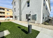 Thumbnail 16 of 17 - A white building with a grey trash can in front of it.