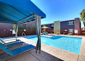 Thumbnail 11 of 23 - A pool area with a blue canopy and a green umbrella.