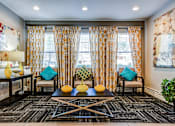Thumbnail 12 of 20 - A living room with a black and white patterned carpet and a large window with curtains.