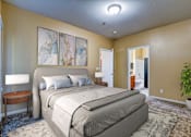 Thumbnail 4 of 20 - A bedroom with a large bed, a lamp, and a plant.