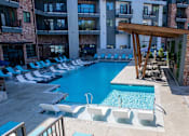 Thumbnail 16 of 21 - A large swimming pool with lounge chairs and a wooden pergola at Sterling Nashville West Apartments, Tennessee, 37209