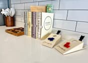 Thumbnail 24 of 35 - a row of books on a counter next to a shelf of chess pieces