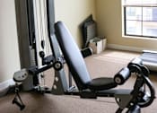 Thumbnail 11 of 18 - A home gym setup with a weight machine and a bench.