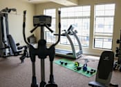 Thumbnail 17 of 18 - A gym with a treadmill, weights, and exercise equipment.